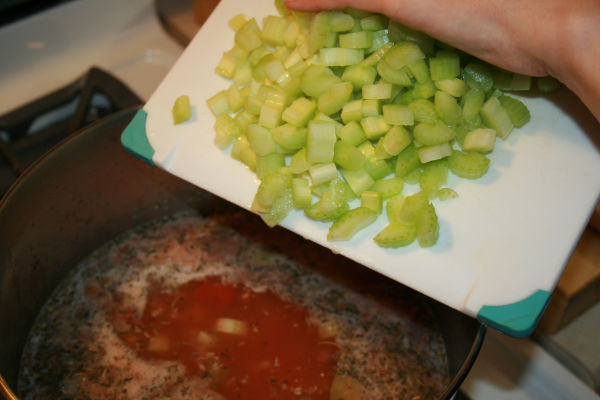 adding the chopped celery to the lentil soup