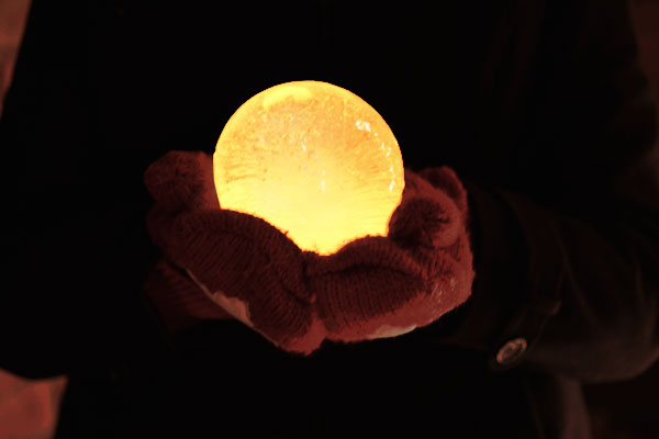 Glowing ice luminary held in a gloved hand