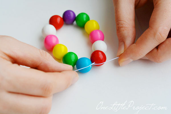 edible gum ball necklace_ hands tying gumball necklace