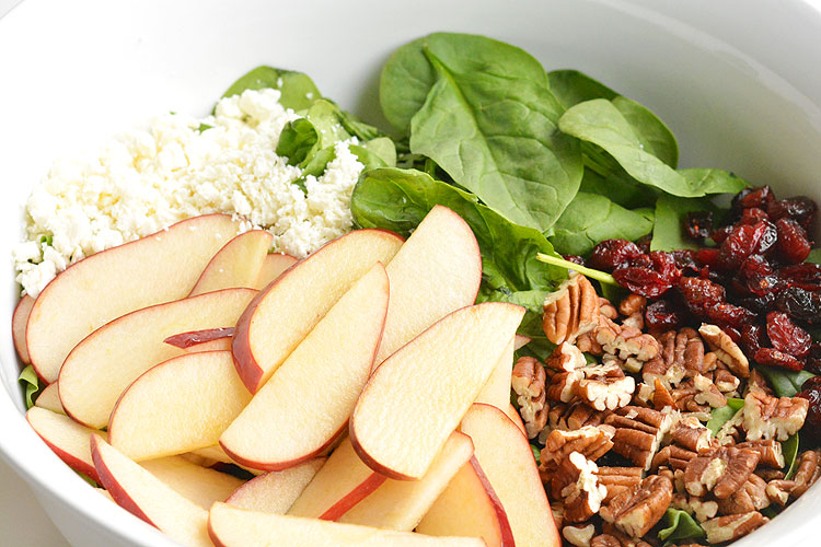 Apple pecan spinach salad in a white bowl