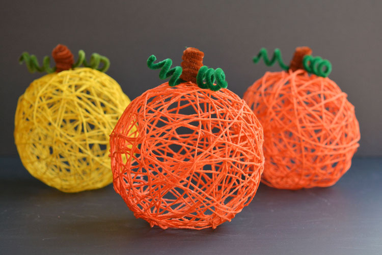 Three yarn pumpkins against a grey background