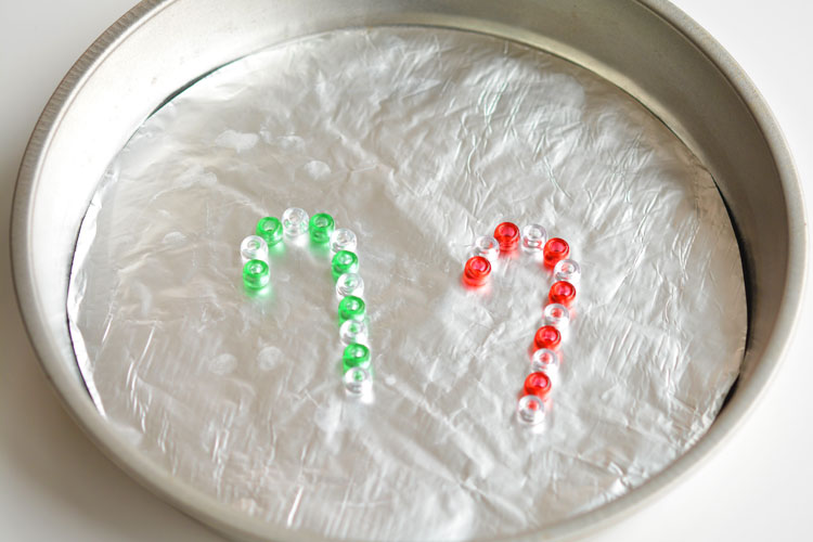 These melted bead candy canes are SO EASY to make with pony beads and they're the cutest homemade Christmas ornaments ever! They look beautiful on the tree, or you can use them as sun catchers in the window!