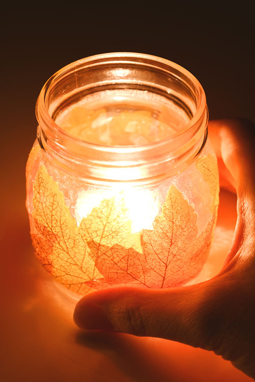 Lit leaf mason jar lantern held in hand