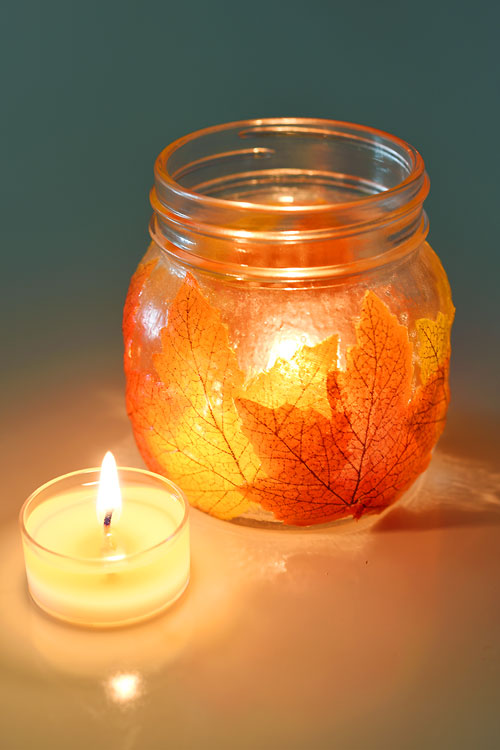Mason jar leaf lantern with lit tealight candle beside it