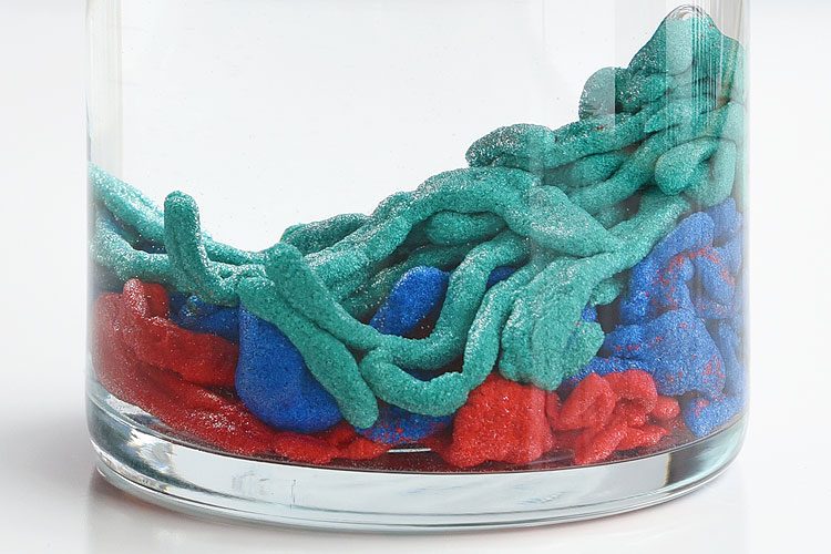 Colourful sand strings in a jar with water