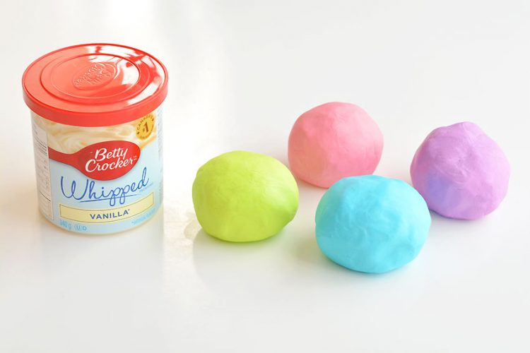 Colourful frosting play dough balls sitting beside frosting container