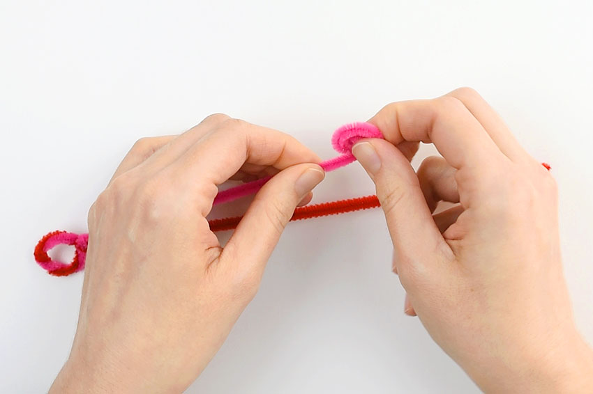 One pipe cleaner being rolled towards the twisted loop