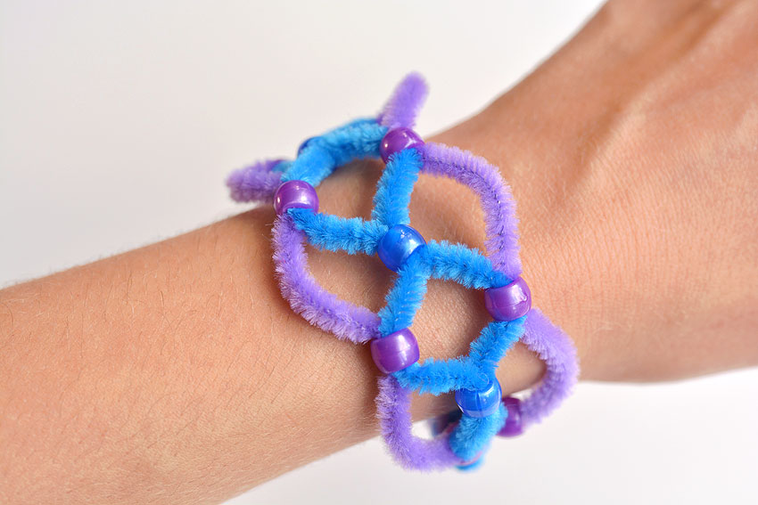 A purple and blue beaded pipe cleaner bracelet on a wrist