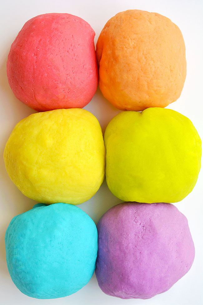 6 balls of coloured playdough on a white background
