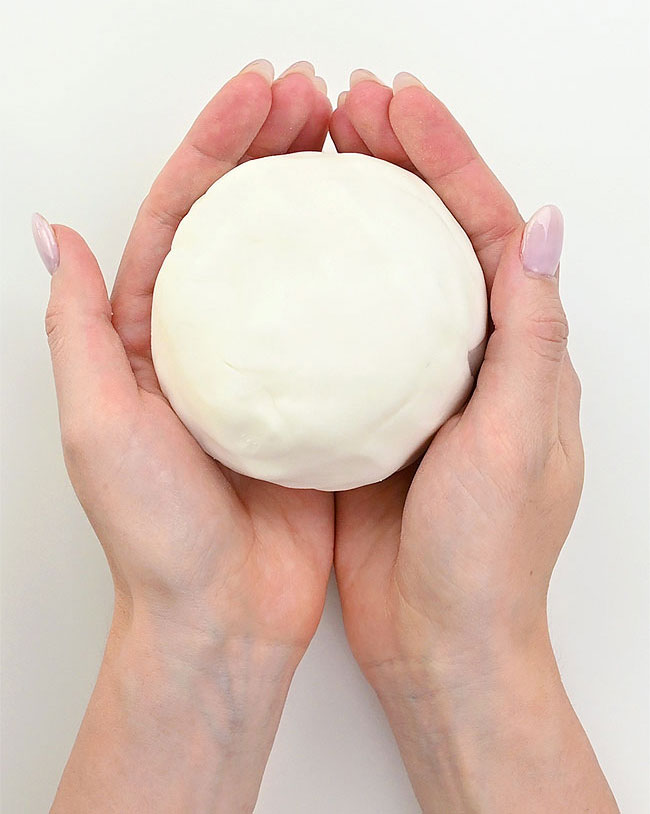 Two hands holding a ball of white clay