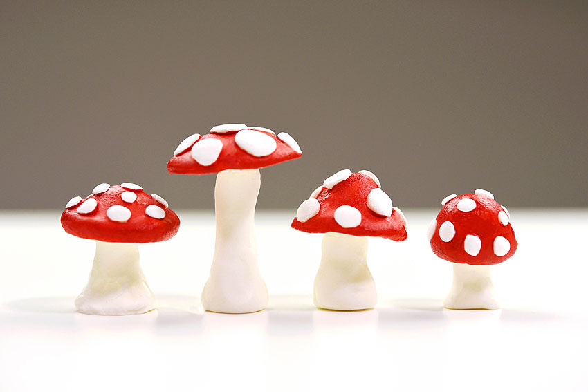 Quatre champignons d'argile tachetés debout dans une rangée