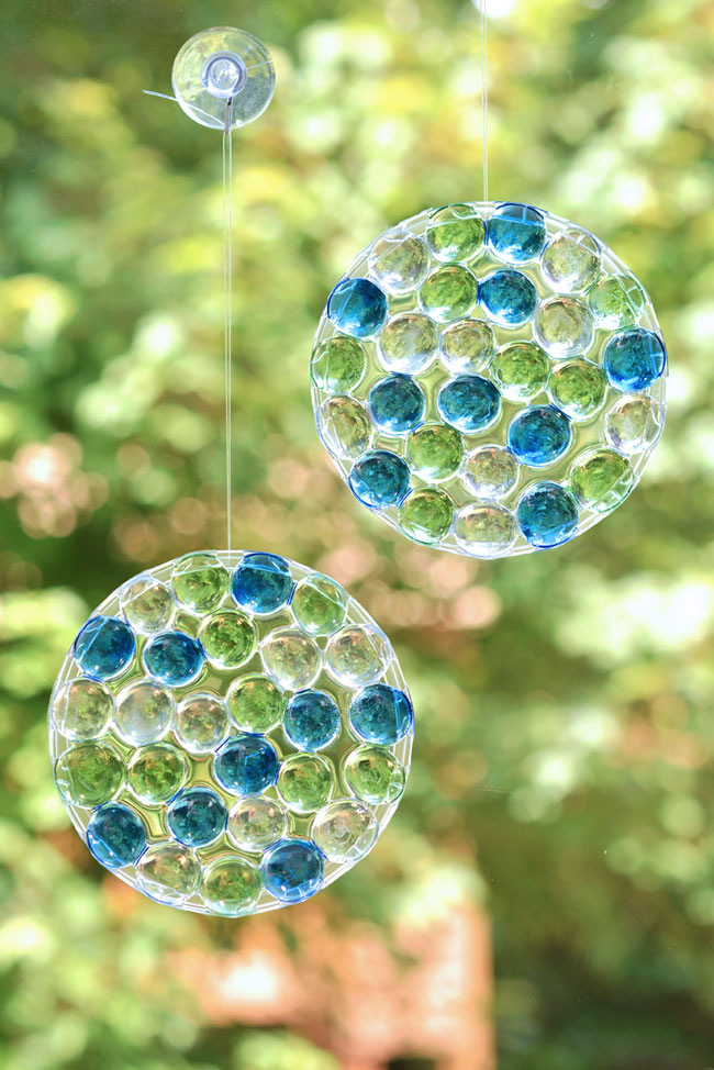 Two DIY suncatchers with glass beads hanging in a window