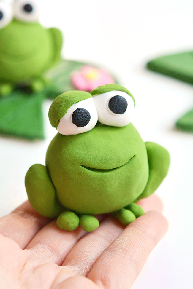 Frog made of clay sitting on fingertips