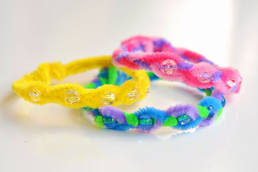 Three pipe cleaner bracelets with beads sitting on a white background