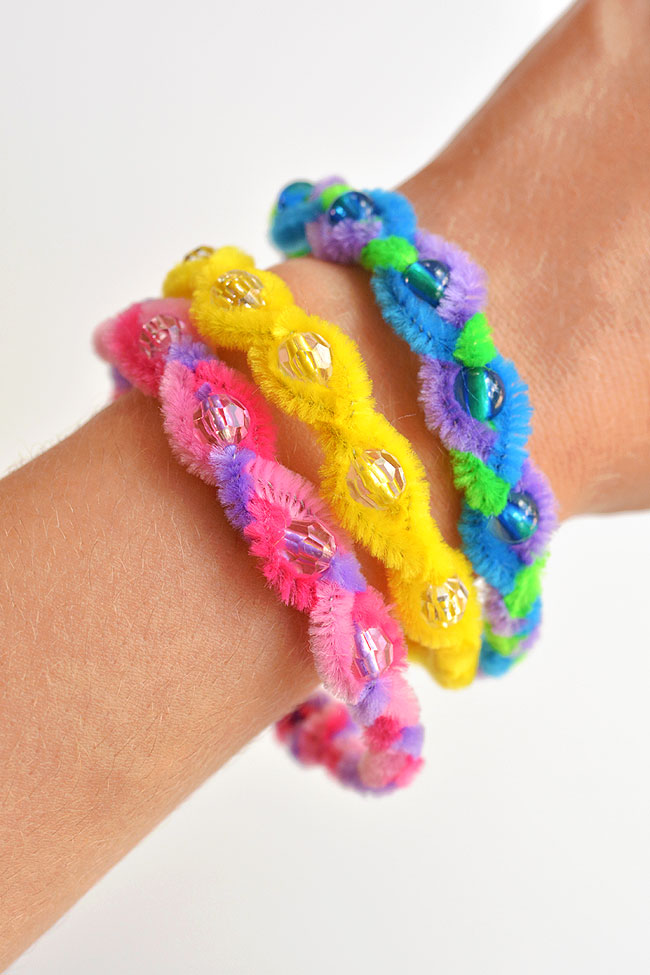 Three different colored pipe cleaner bracelets on a wrist