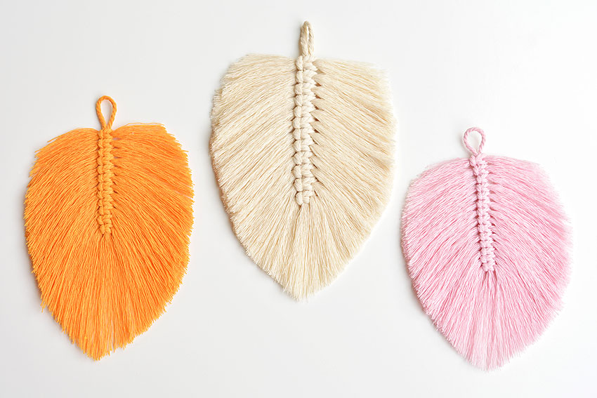 Three feathers from macrame cord on a white background