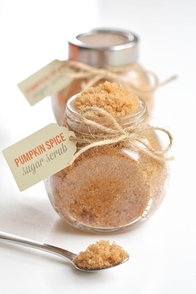 A spoon of pumpkin spice sugar scrub in front of labeled jars