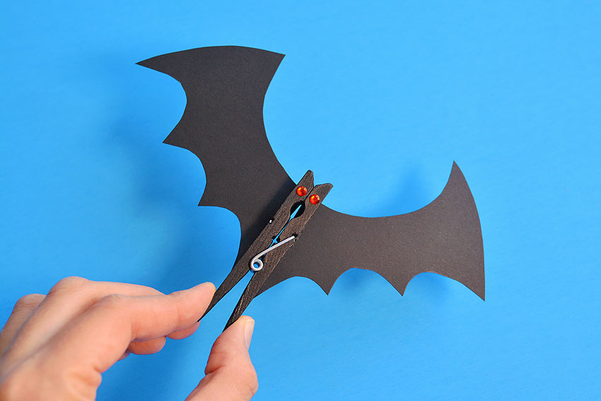 Bat clothespin held against a blue background