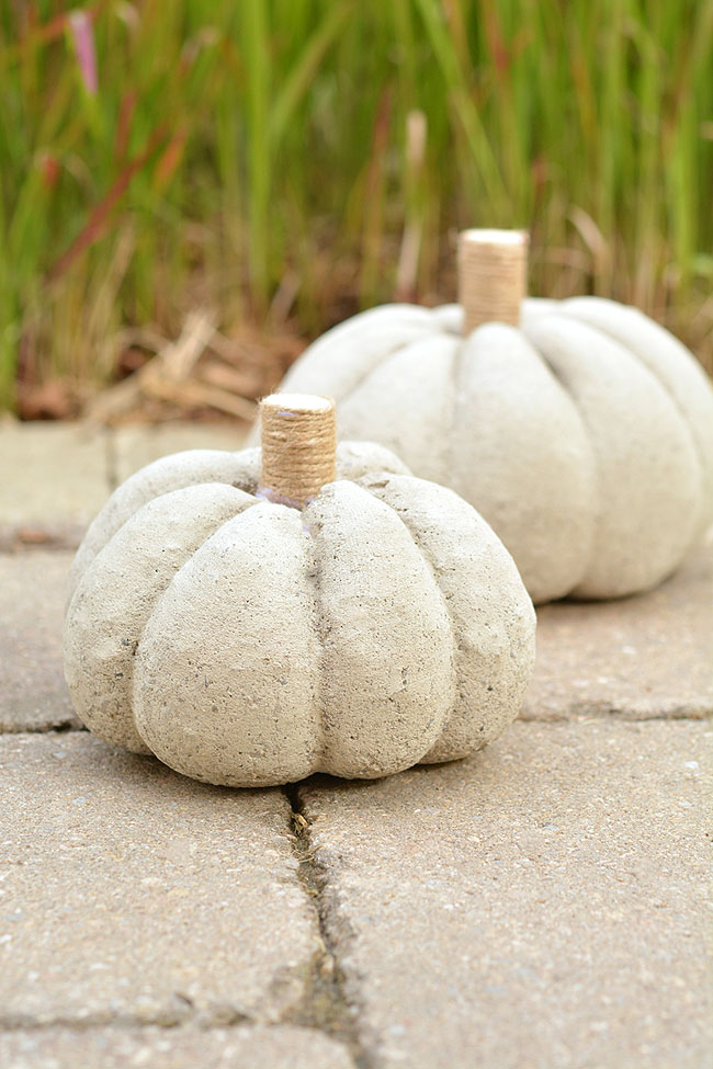 Two concrete pumpkins sitting outside