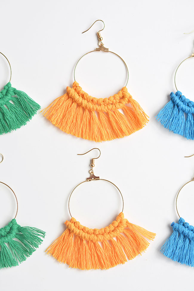 Orange DIY macrame earrings surrounded by green and blue pairs