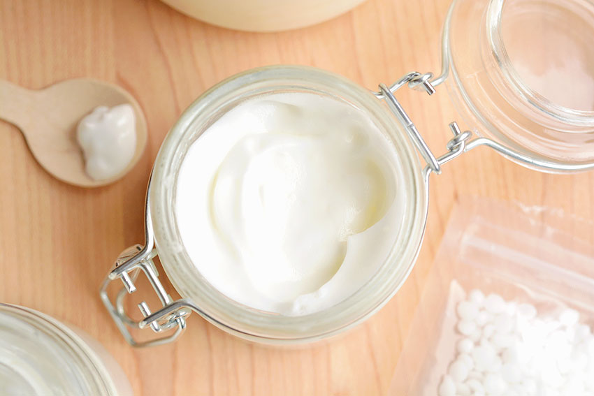 Jar of lotion surrounded by ingredients for making shea butter lotion