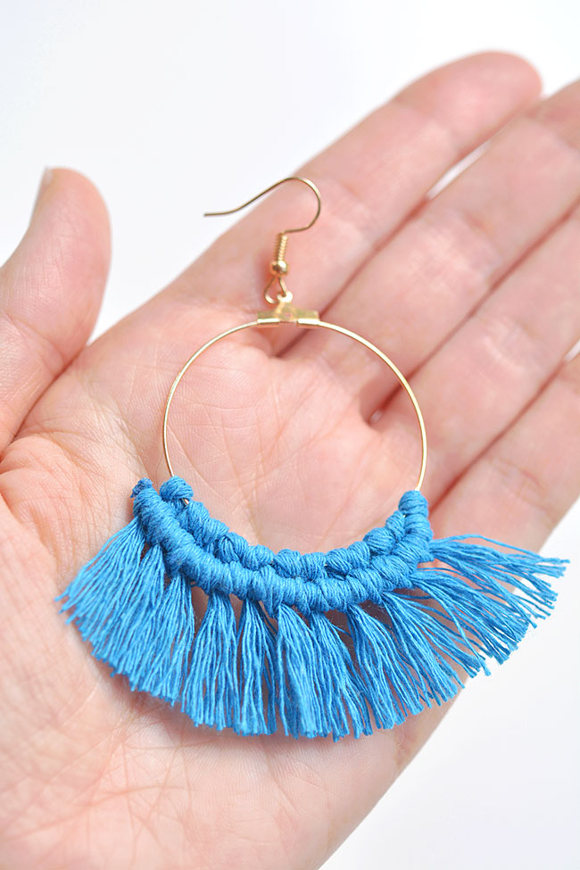 Blue macrame earring held in a palm