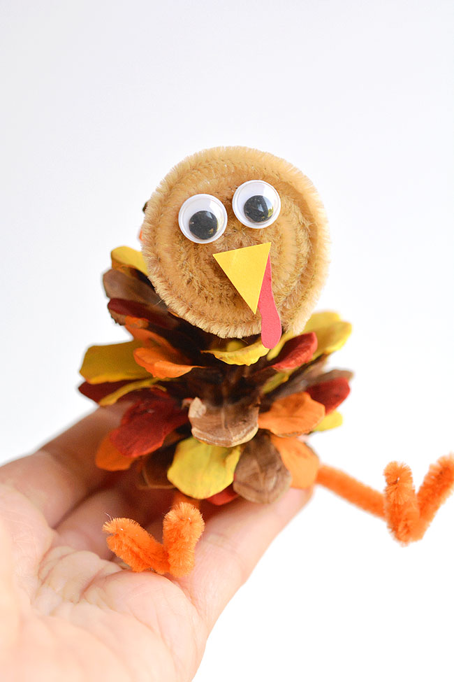 Pinecone turkey craft held on a hand