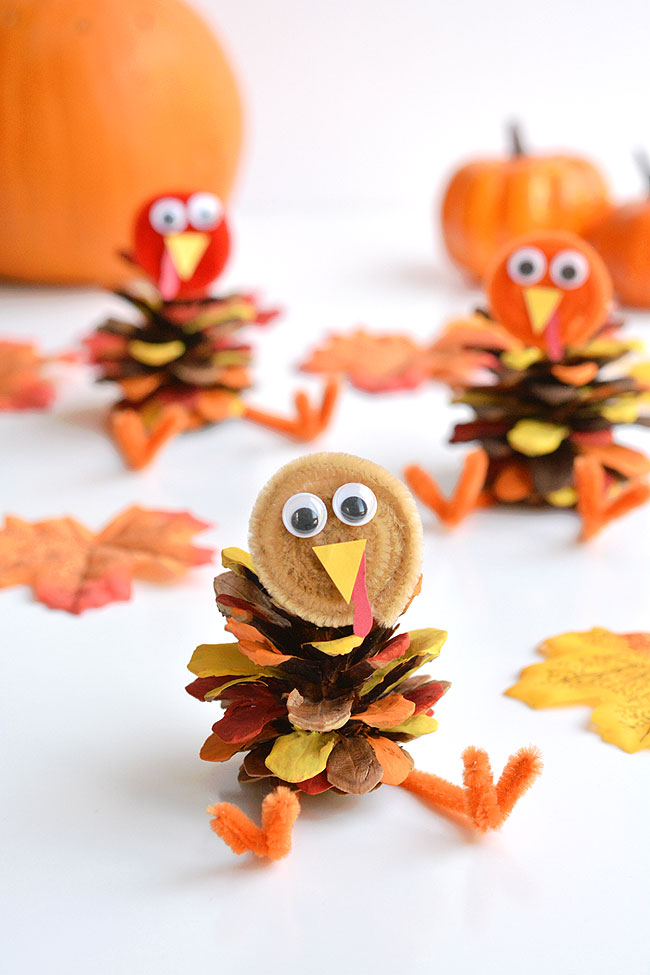 Pinecone turkeys surrounded by leaves and pumpkins