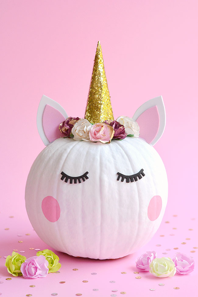 Pumpkin decorated like a unicorn with a glitter horn and a flower crown