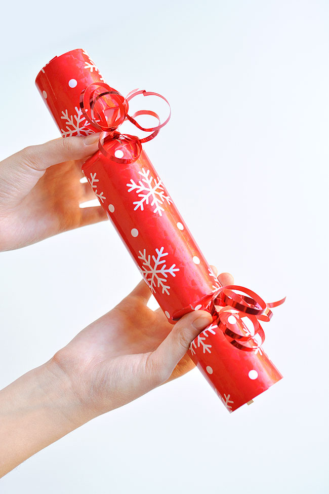 Two hands holding a red Christmas cracker