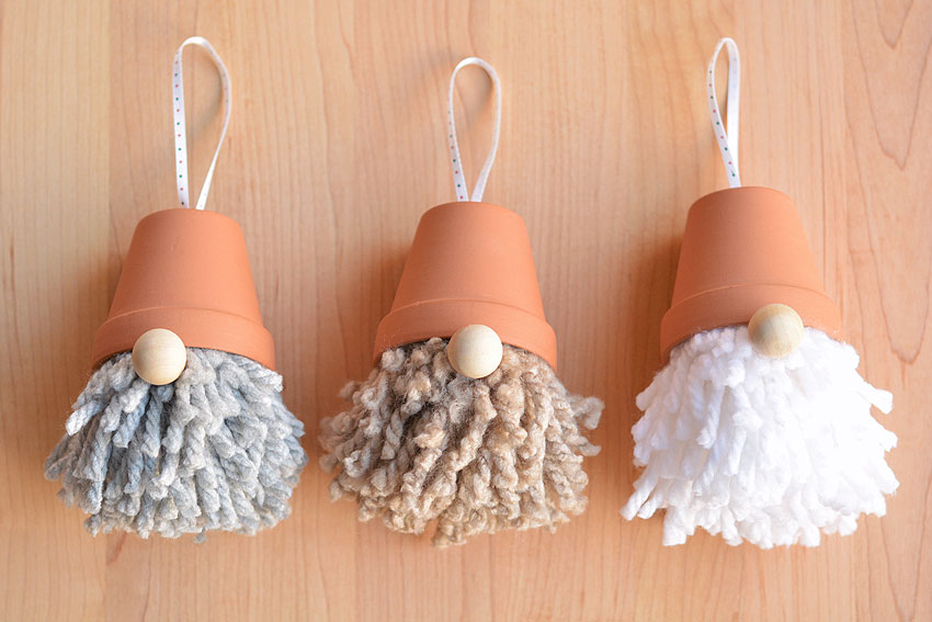Three DIY gnome ornaments lying on a wooden background