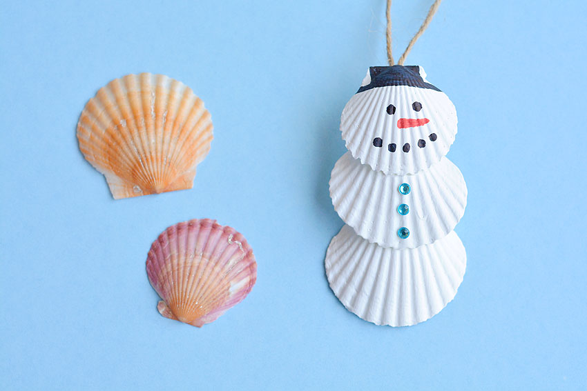 Finished seashell snowman ornament next to two seashells