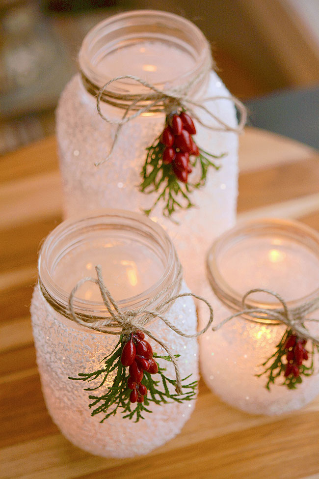 Three snowy mason jar luminaries with candles inside