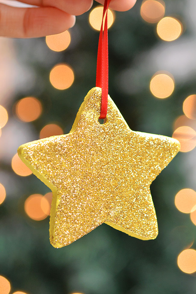 Gold star shaped salt dough ornament hanging from a red ribbon