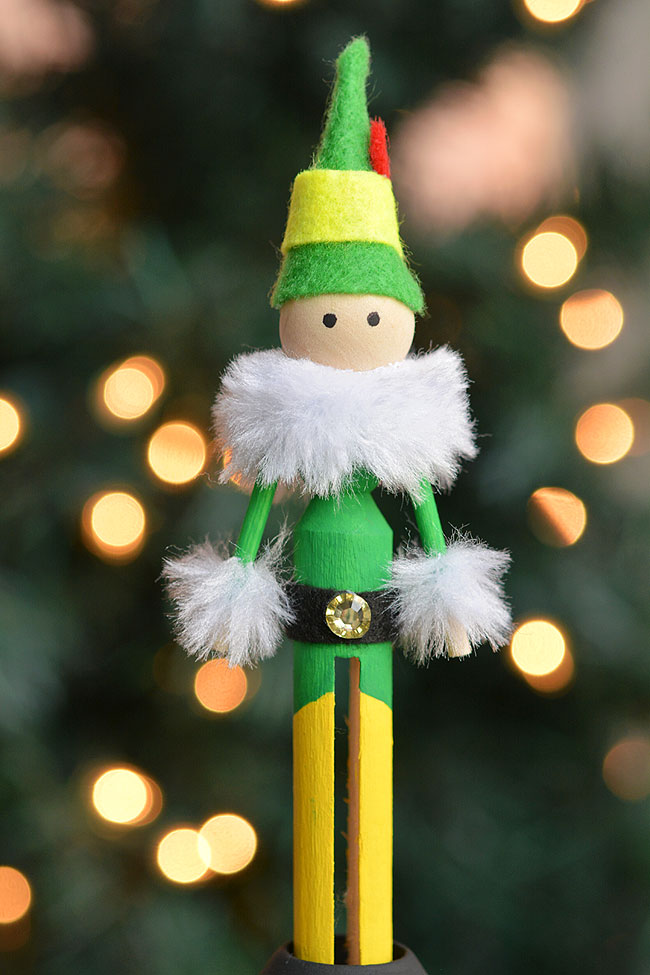 Green wooden peg elf in front of the Christmas tree