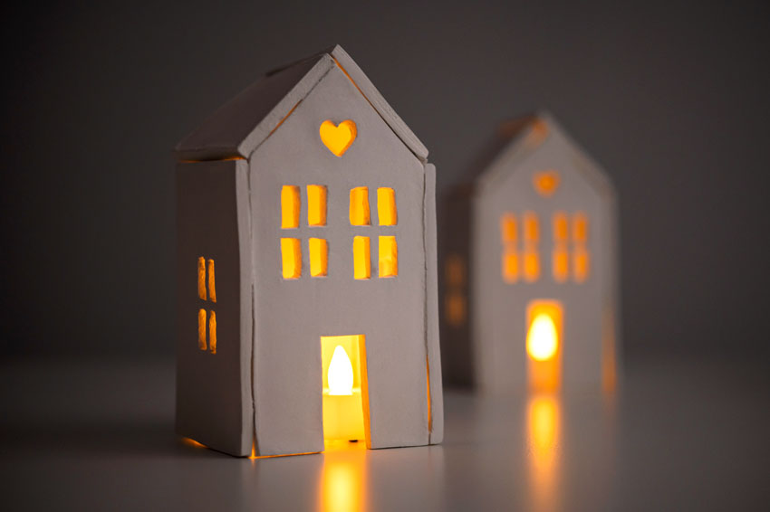 Candle holders shaped like houses with tealights lit inside