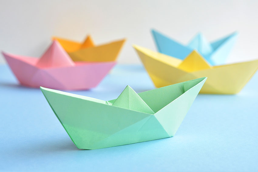 Colourful origami paper boats on a blue surface