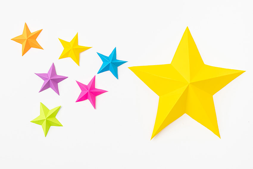 A large yellow paper star beside a group of small, colourful paper stars