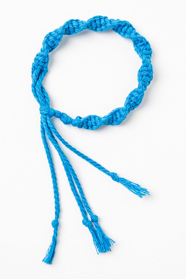 Closeup of a blue macrame bracelet made with a half knot spiral