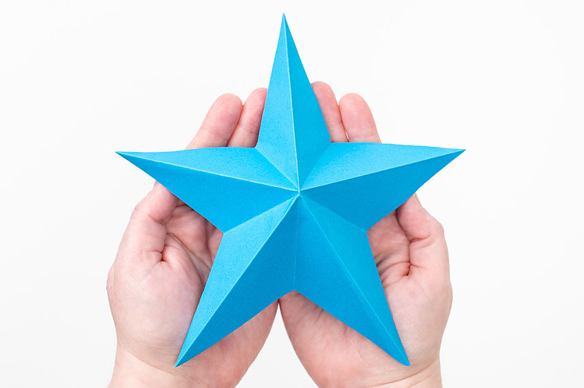 Blue origami star held in hands