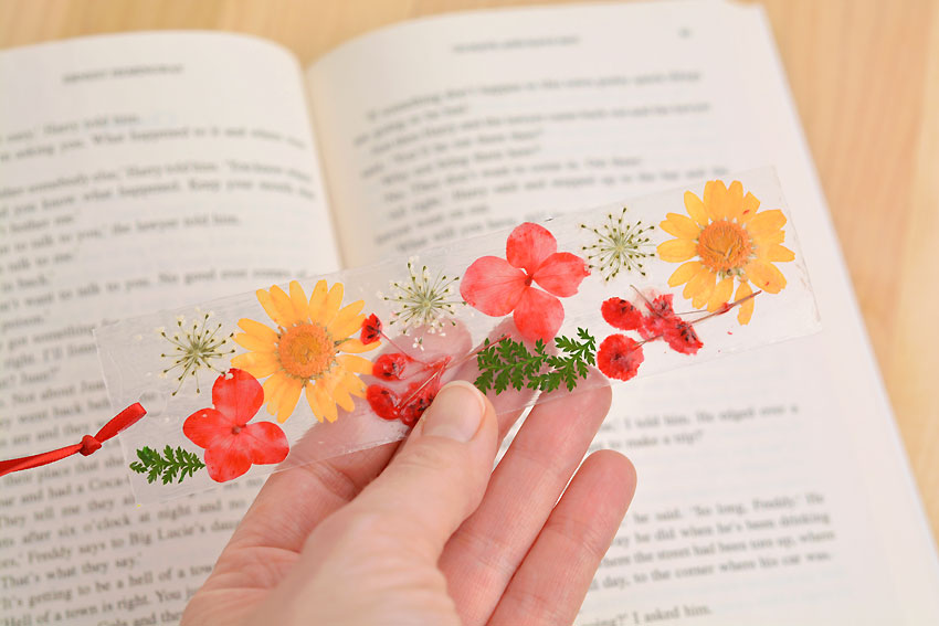 Dried flower bookmark held above a paperback book