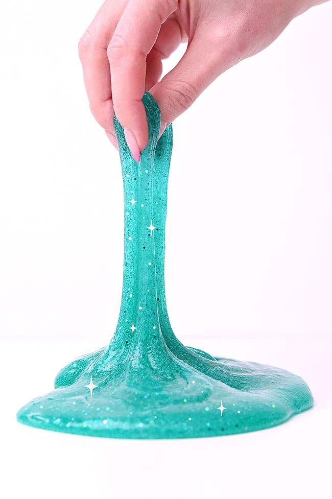 Glittery blue mermaid slime falling into an ocean like puddle