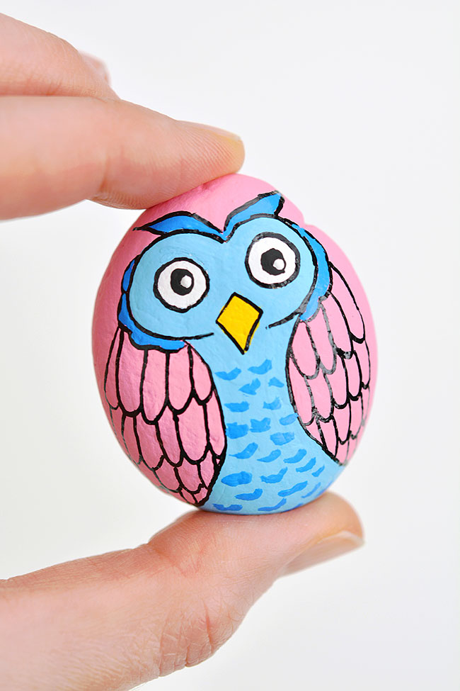 Closeup of a pink and blue owl rock painting