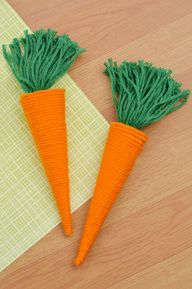 Yarn carrot decorations for Easter on a wooden and patterned background