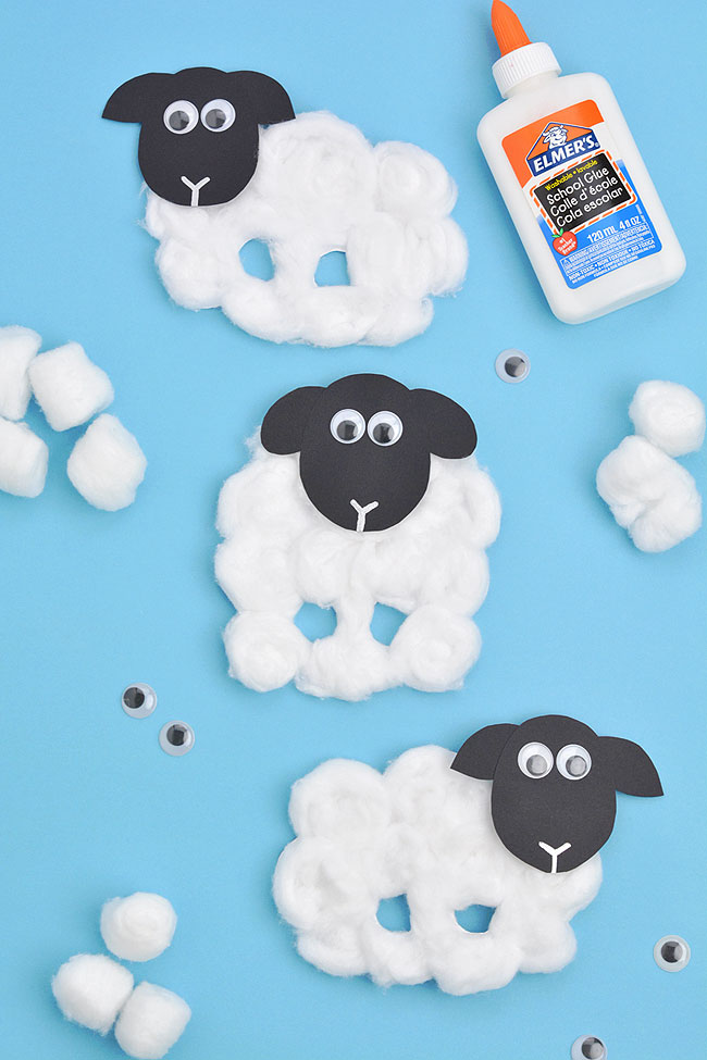 Sheep craft surrounded by cotton balls, googly eyes, and glue