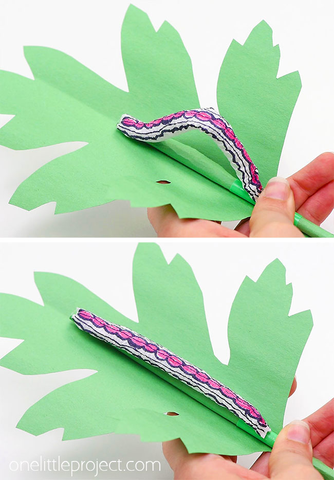 Pink coloured caterpillar craft wriggling on a paper leaf