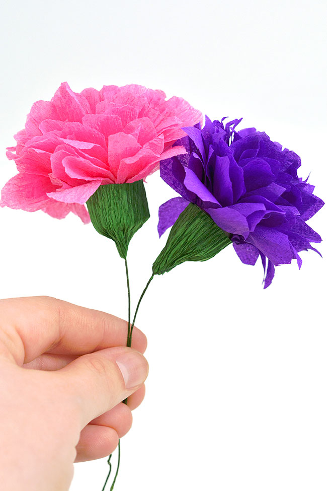 Pink and purple crepe paper flowers held in a hand
