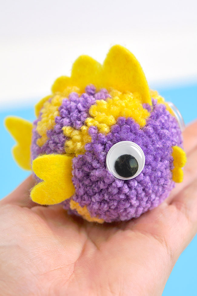 Closeup of a purple and yellow pom pom fish craft