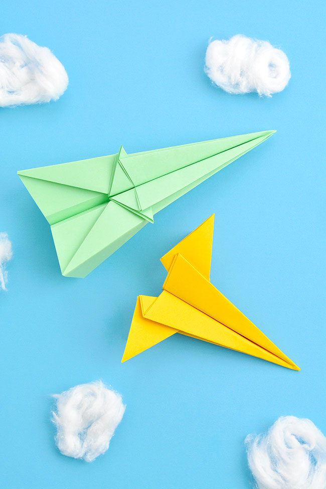 Two different jet paper airplanes on a sky blue background