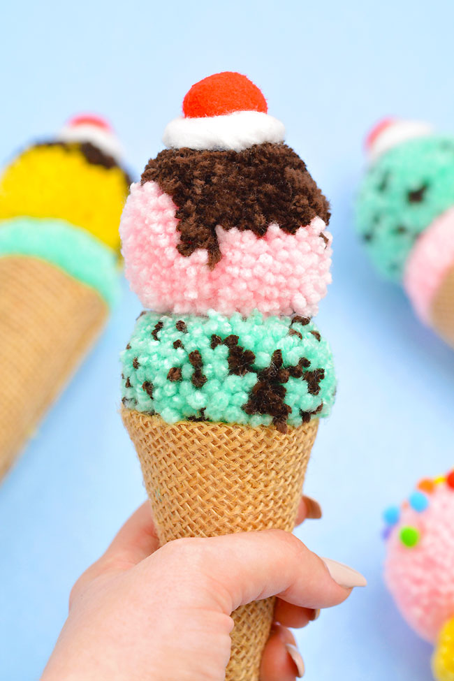 Closeup of a hand holding an ice cream cone pom pom